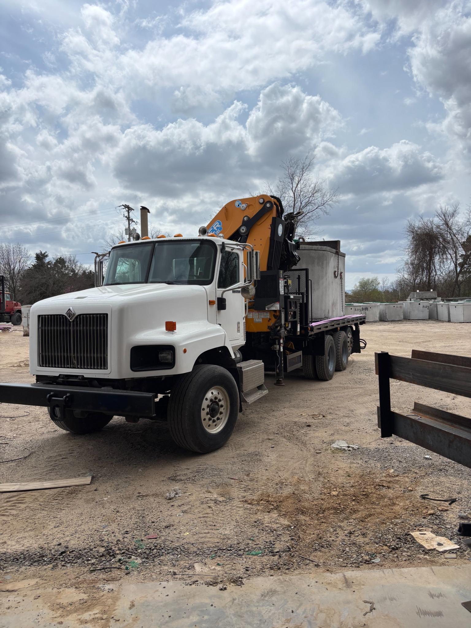 Knuckleboom truck delivering tank