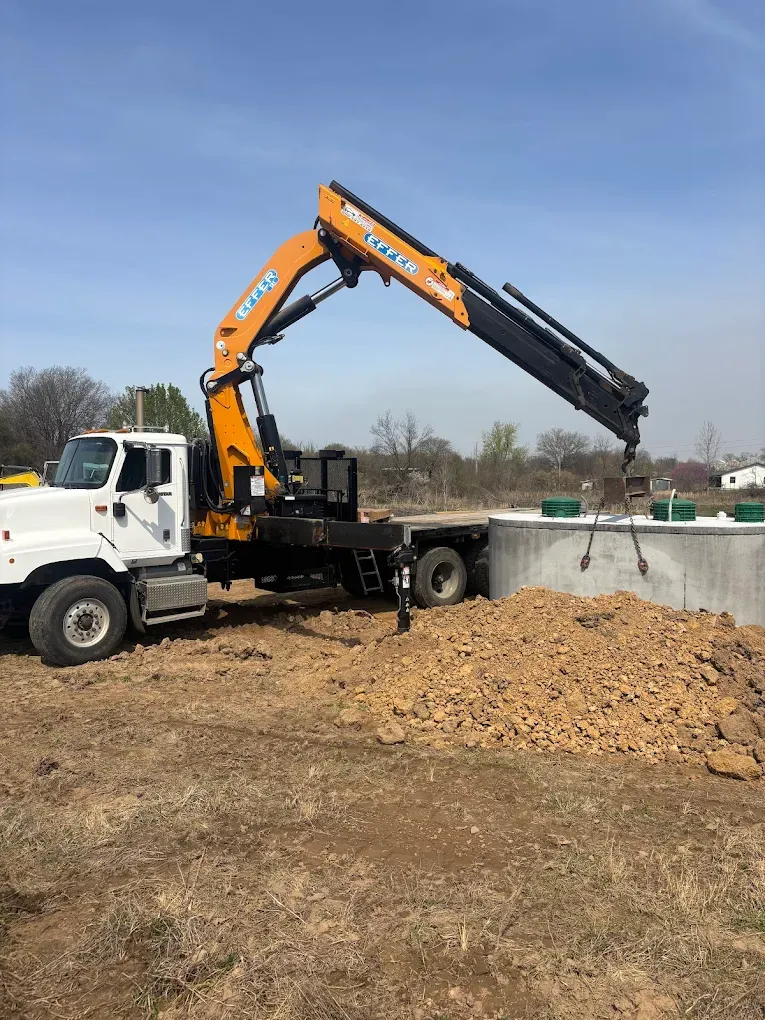 Knuckleboom truck placing a concrete septic tank